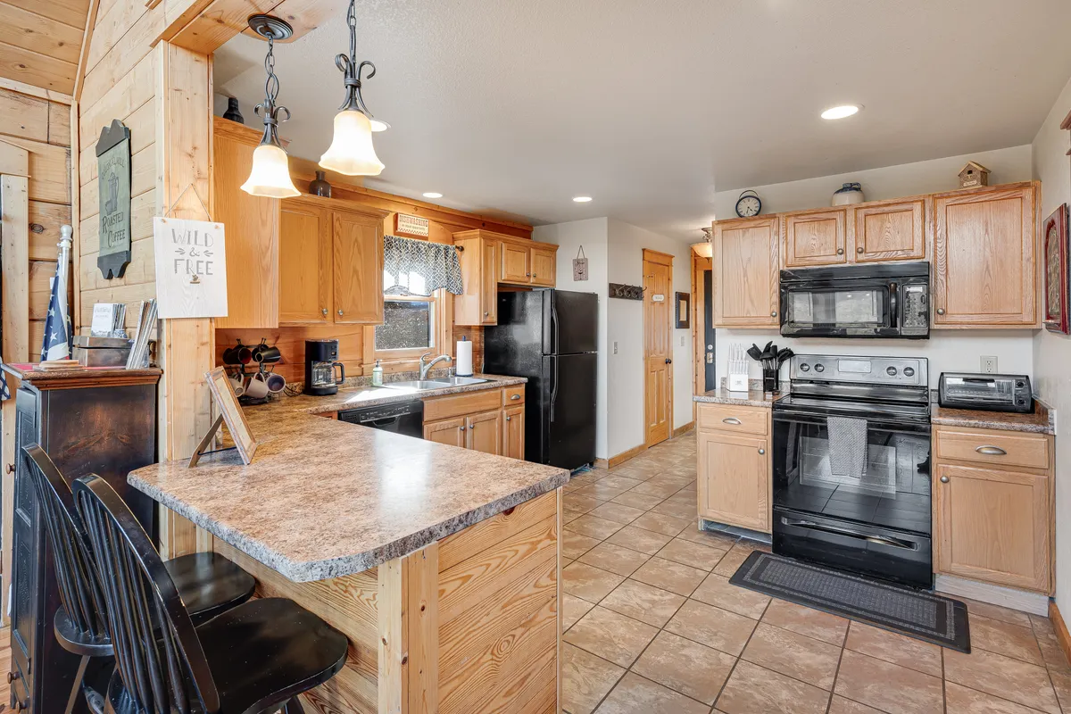 This photo highlights a well-equipped kitchen with a central island, stainless steel appliances, and warm wooden cabinetry. Pendant lights add a cozy ambiance, while the open layout encourages interaction during meal prep and casual gatherings.